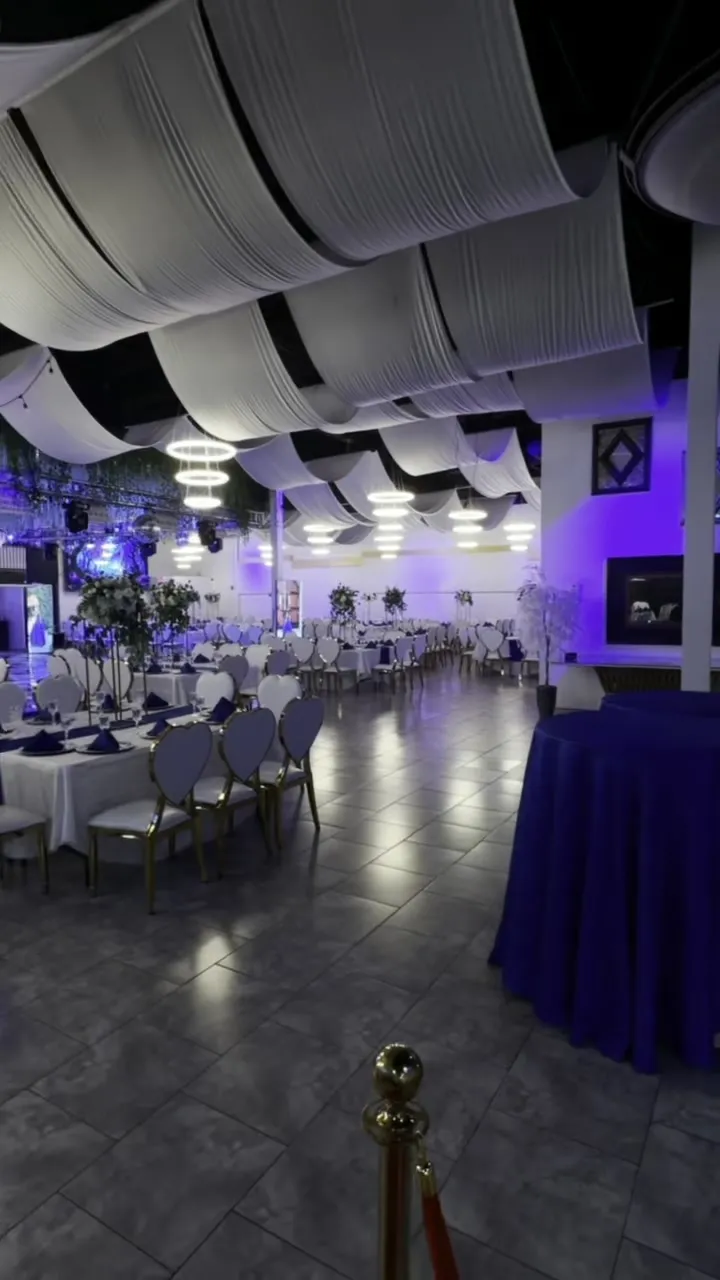Vista amplia del salón con mesas de banquete e iluminación violeta.