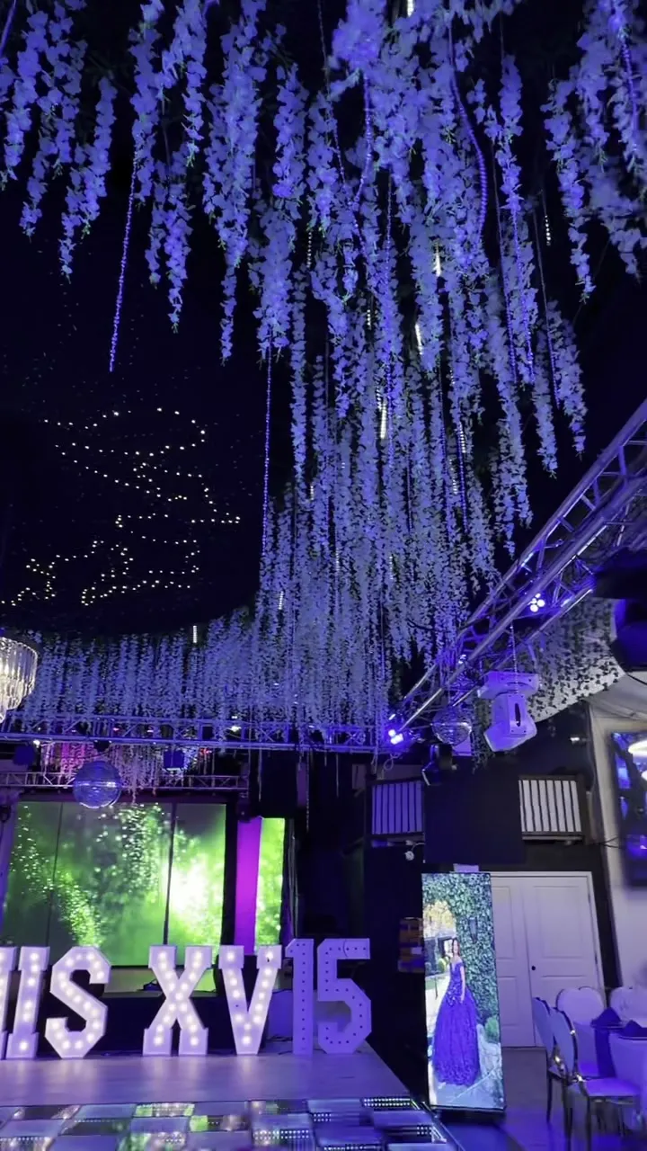 La barra del salón, iluminada desde abajo, con letrero de neón e iluminación colgante.