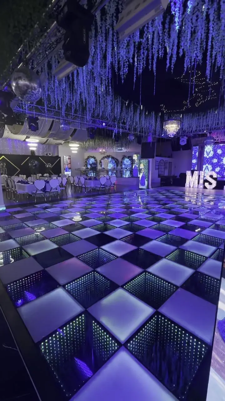 La pista de baile iluminada a cuadros bajo un techo colgante de flores.