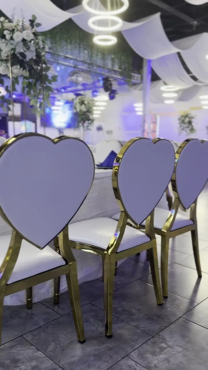 Sillas de banquete con marco dorado en una mesa vestida de blanco.