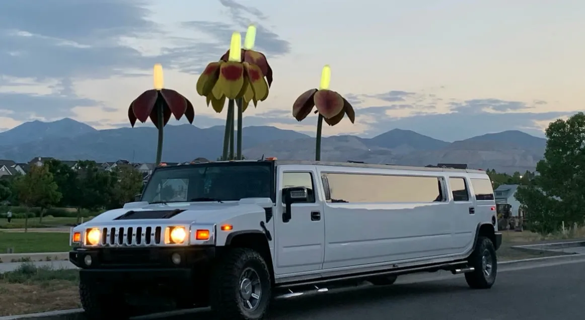 La limusina Hummer blanca estacionada al atardecer con las montañas Wasatch al fondo.