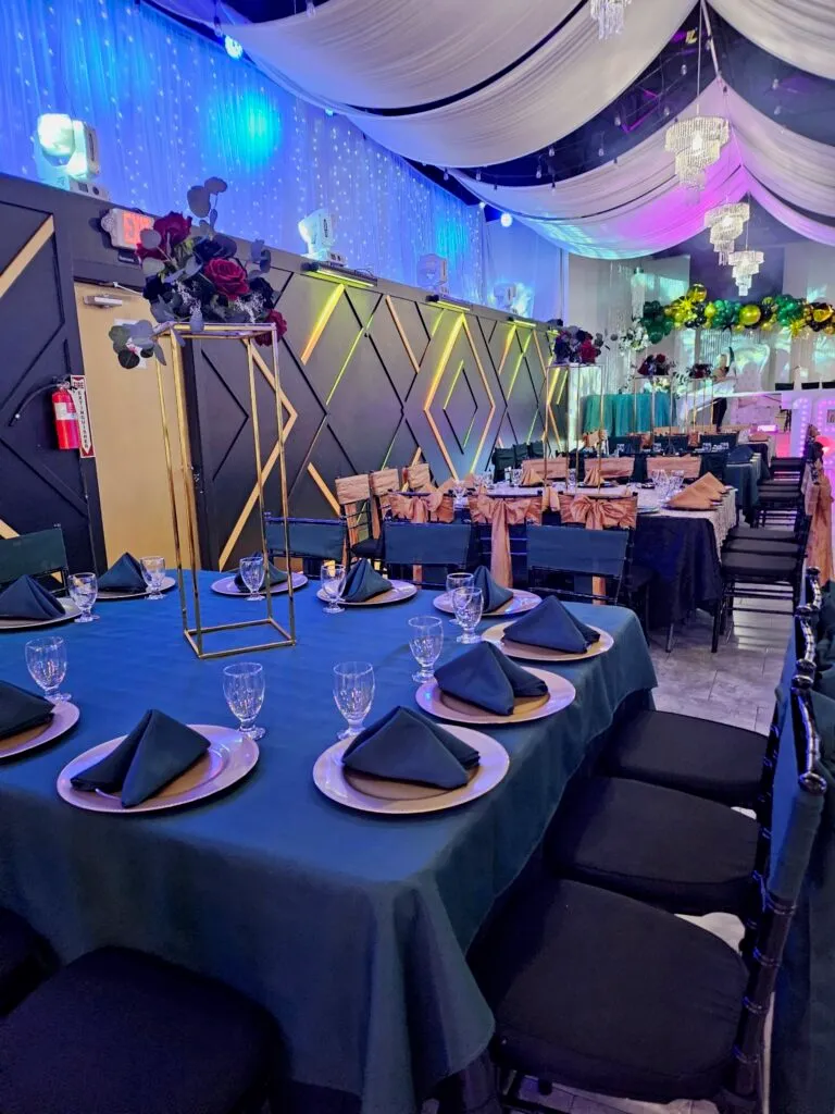 Una mesa vestida en color turquesa con platos base y un centro de mesa floral.